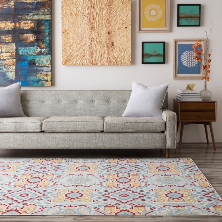Gray couch with colorful area rug in front.