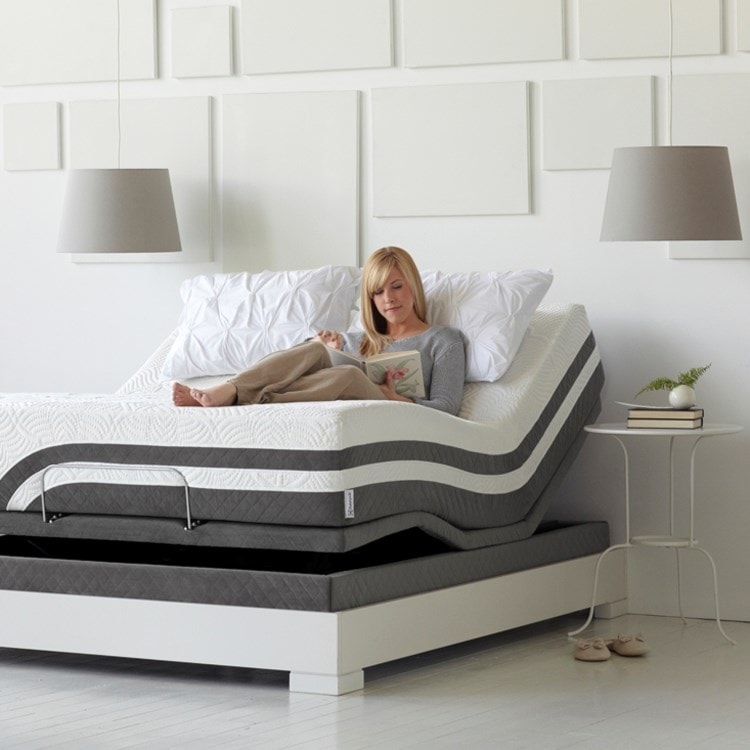 Woman sitting up reading in an angled bed.