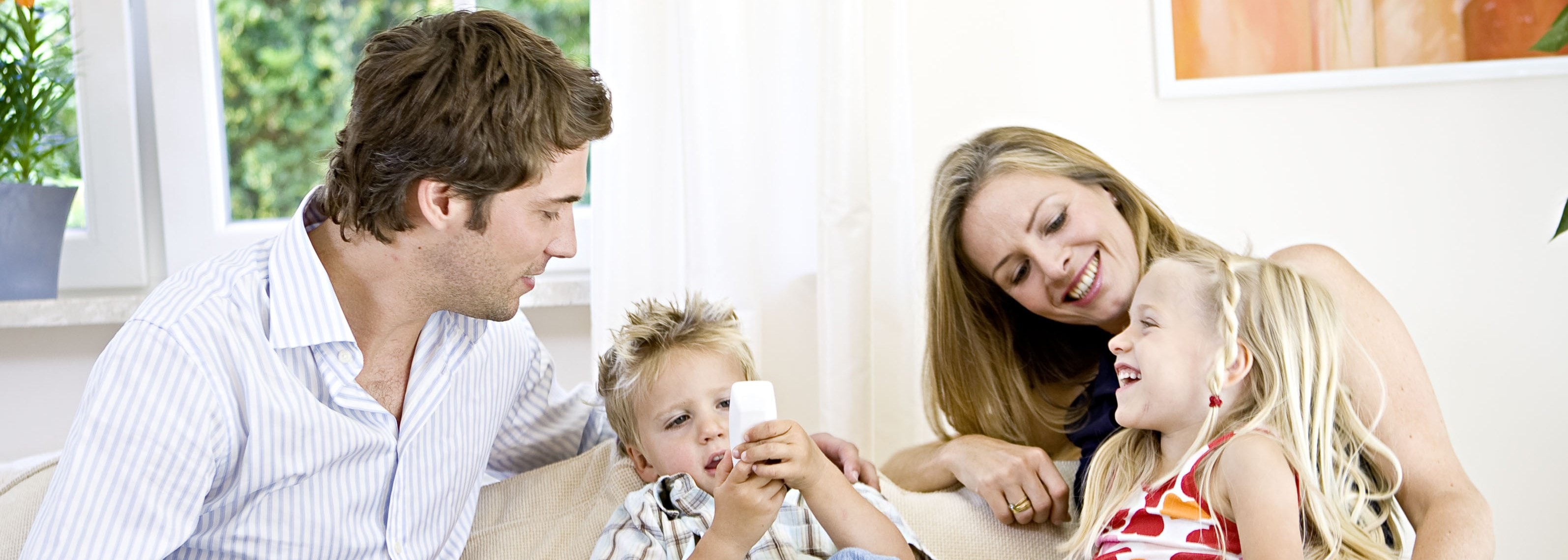 Family of four sitting together on the couch.