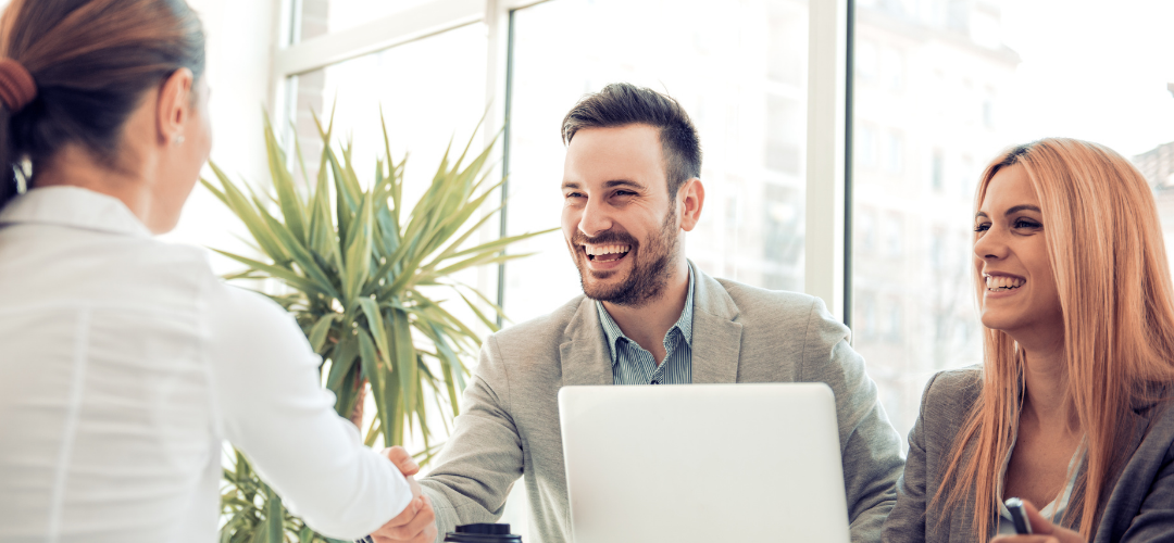 Picture of 3 individuals smiling and shaking hands