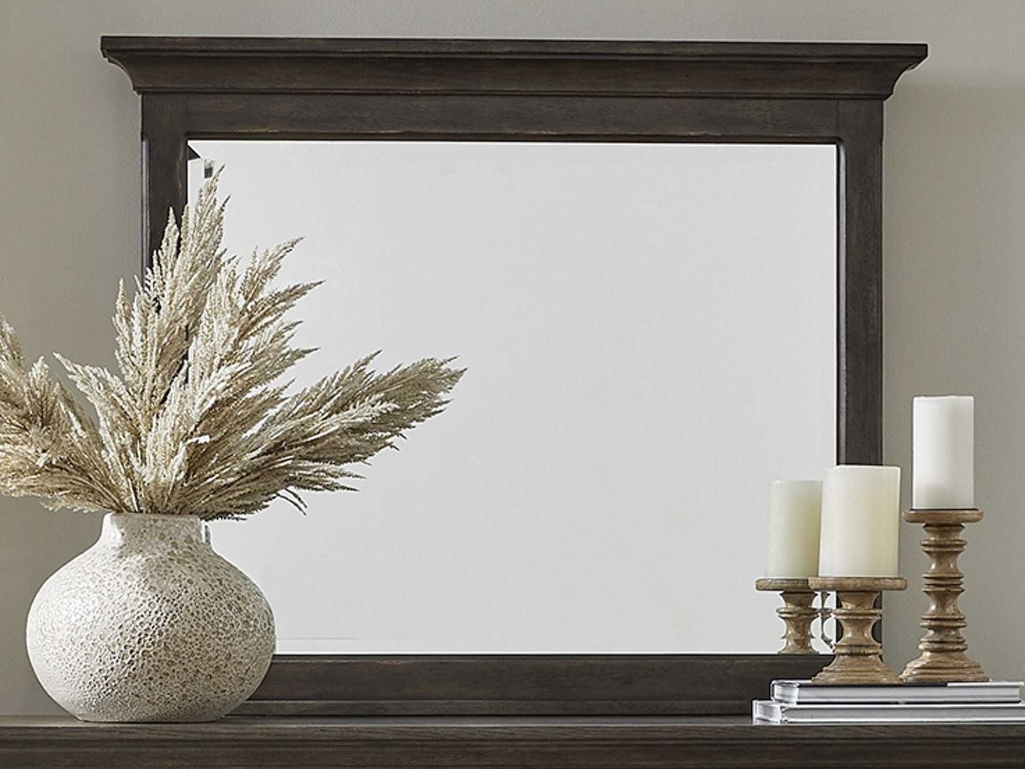 Large mirror propped on dresser with candles and vase nearby