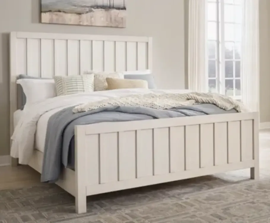 Wooden bed with fluffy comforter and two drawers at foot of bed