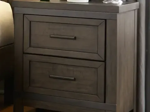 Nightstand next to bed with two drawers and objects on tabletop