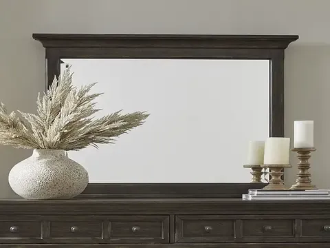 Large mirror propped on dresser with candles and vase nearby