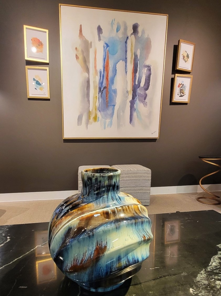 Vase on table with artwork behind
