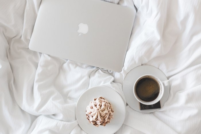 flatlay of macbook and coffee sitting on bed