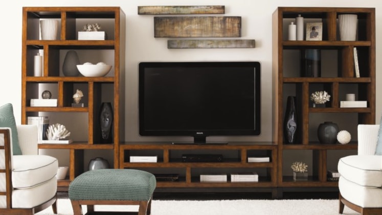 Television on light wood open console with two symmetric bookshelves on either side. 