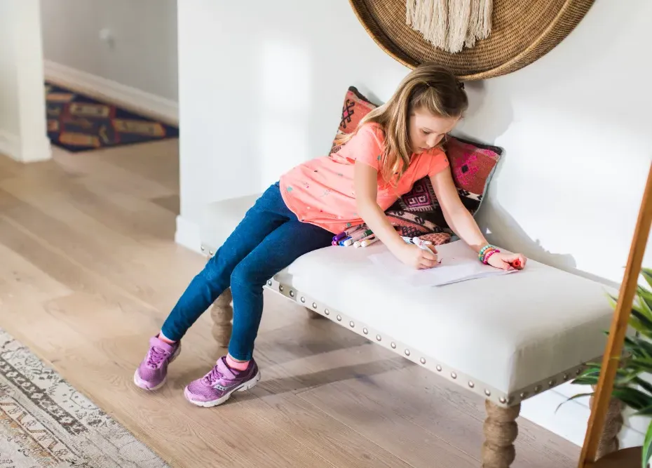 child coloring paper on a fabric bench