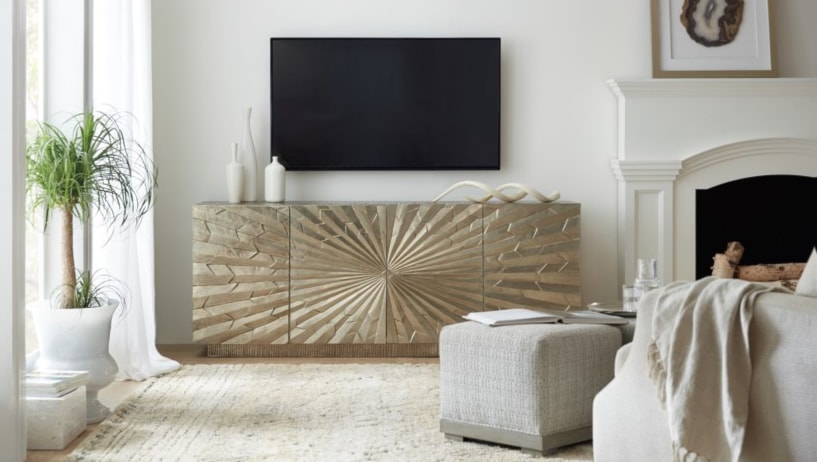 Television over a golden-colored console with a starburst pattern. 