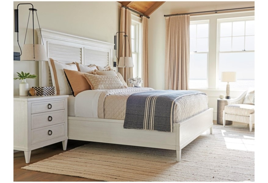 A white bed with a louvered headboard in a bedroom setting. 