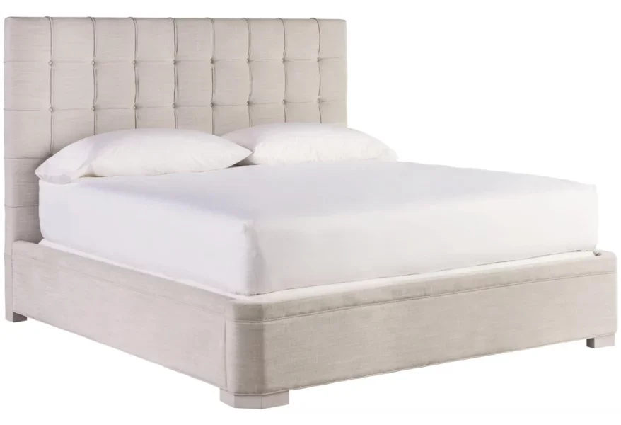 A padded off-white bed with white sheets on the mattress. 