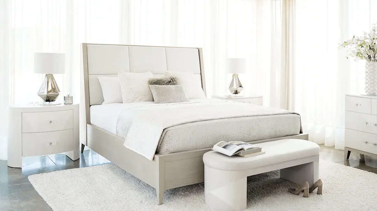 Neutral-colored contemporary bedroom with night stand and bench at the foot of the bed. 