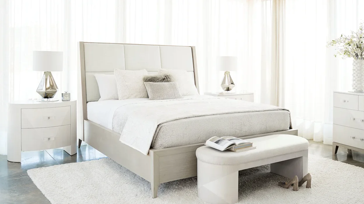 Neutral-colored contemporary bedroom with night stand and bench at the foot of the bed. 