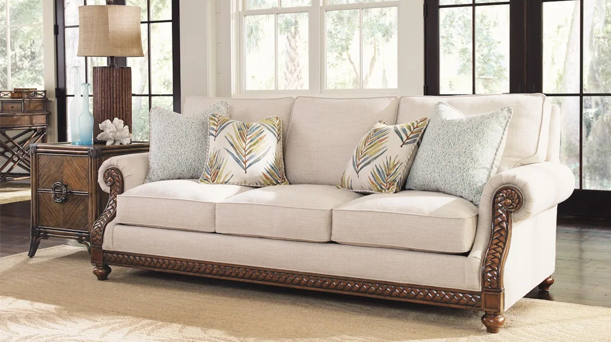 Cream-colored sofa with rolled arms and wooden features in a large living room. 