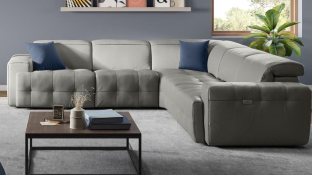 Light gray reclining sectional in room with neutral walls.