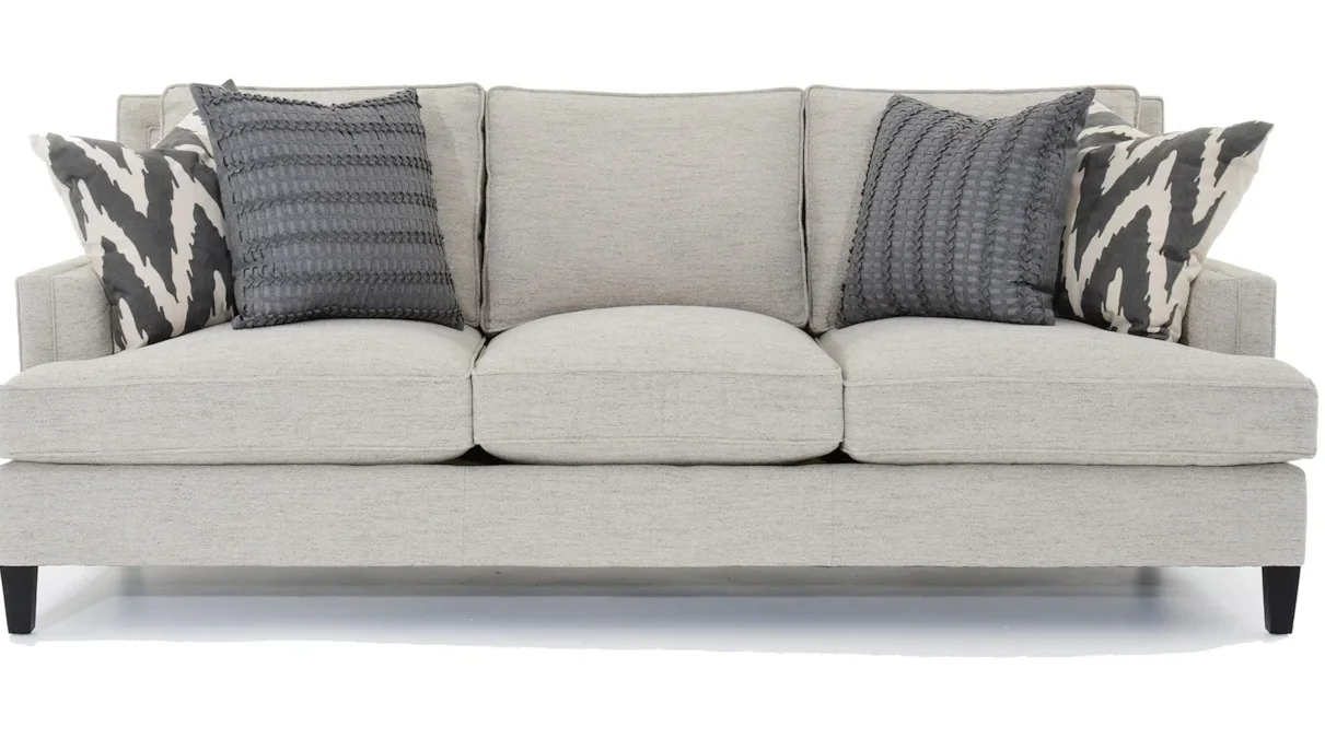 Fabric light gray couch with two sets of throw pillows on it. 