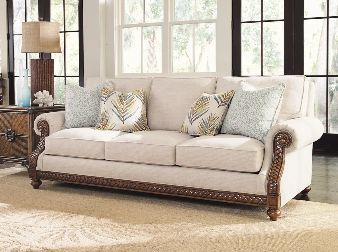 Cream-colored sofa with wood features and rolled arms in a large living room. 