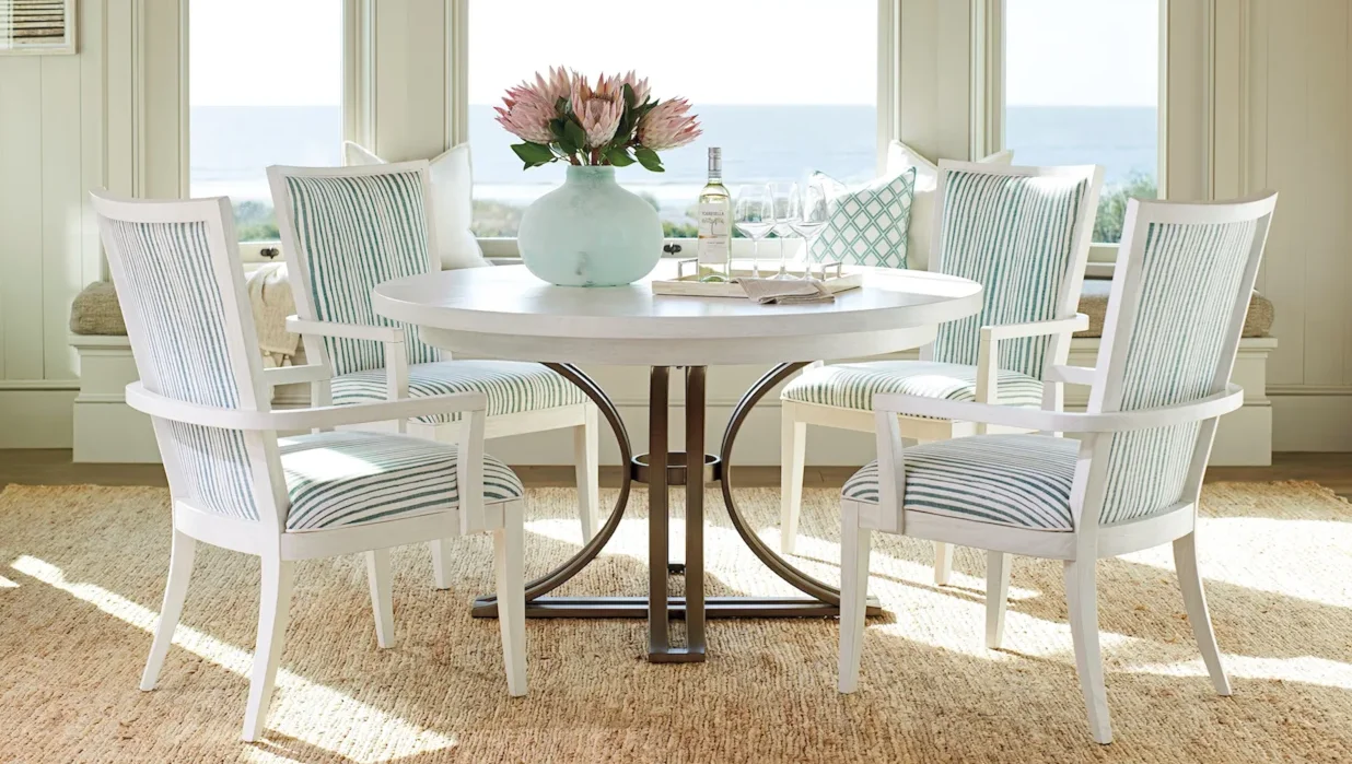 White table with metal base surrounded by four armchairs with striped upholstery. 